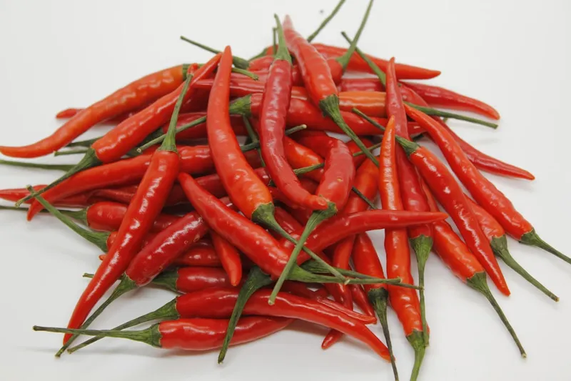 Hot peppers, also known as chili peppers, are fruits from the Capsicum genus, renowned for their fiery flavor, heat, and distinctive taste. These peppers contain capsaicin, a compound that causes the sensation of heat, and varies in concentration, determining the pepper's spiciness. Hot peppers come in a variety of shapes, sizes, and colors, ranging from small, slender varieties like bird's eye chilies to larger ones like jalapeรฑos and habaneros, as well as the extremely hot Carolina Reaper and ghost pepper.